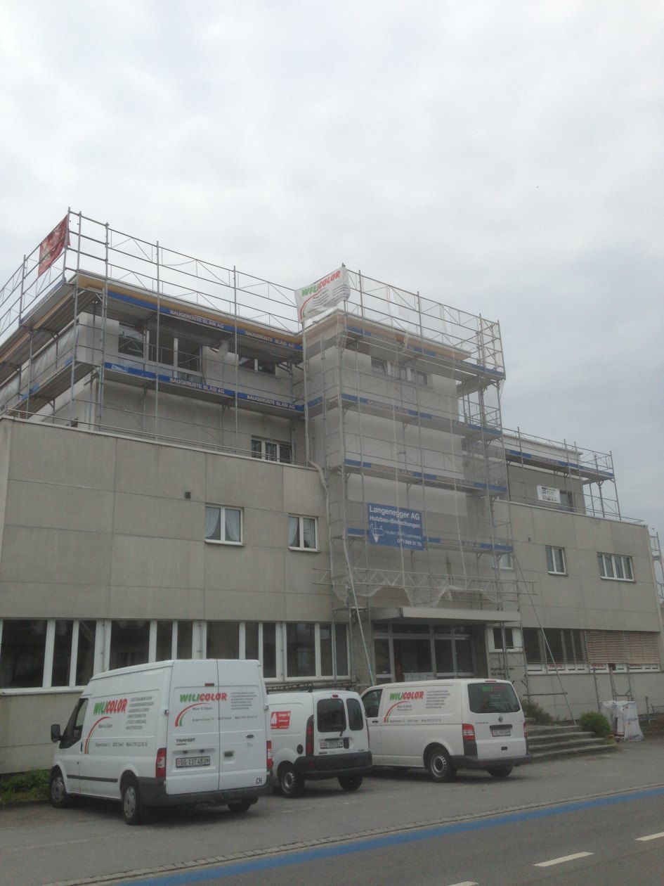 Wilicolor Fahrzeuge vor einer Fassade mit Geruest