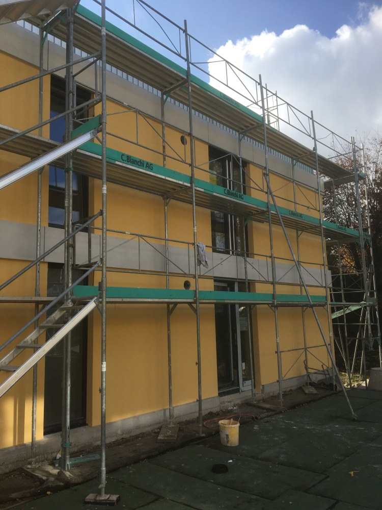 Fassade mit Geruest und gelber Daemmung